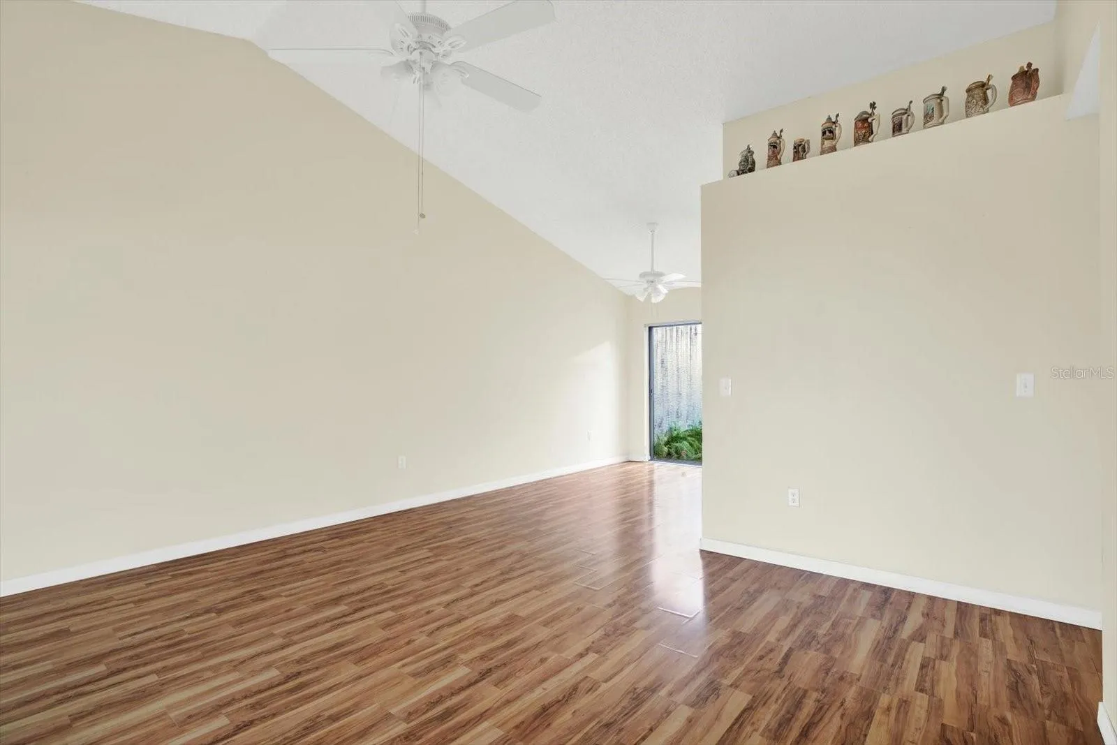 A second view of the open living space, with a ceiling fan and wood-look laminate flooring.