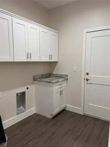 inside laundry with cabinets and granite countertop