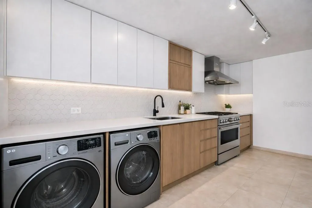 Kitchen: Modern kitchen with ample cabinetry, generous counter space, stainless-steel appliances, washer and dryer. AI-generated/AI-enhanced image for illustrative purposes.