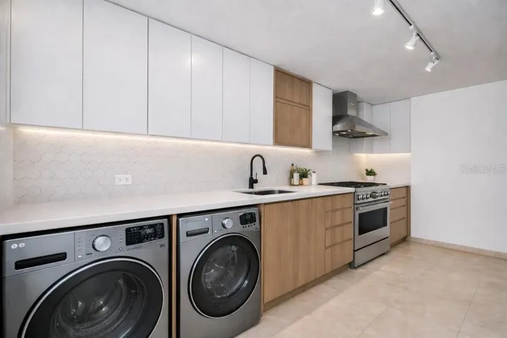 Kitchen: Modern kitchen with ample cabinetry, generous counter space, stainless-steel appliances, washer and dryer. AI-generated/AI-enhanced image for illustrative purposes.