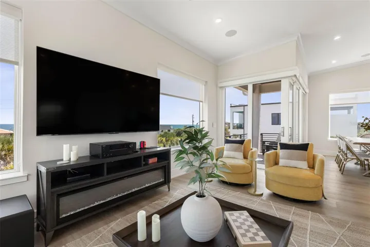Enjoy vibrant ambiance with a modern multi-color electric fireplace, stylish built-ins, and peekaboo ocean views