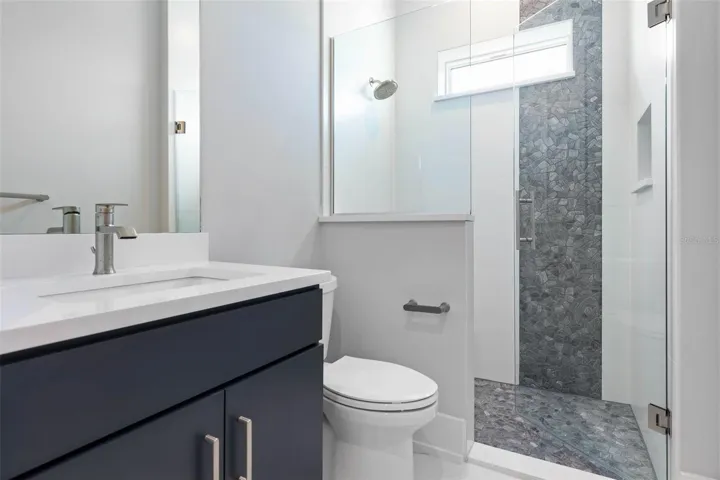 This sleek guest bathroom features a modern vanity, walk-in shower with striking  tile accents, and clean contemporary finishes for a fresh, polished look.