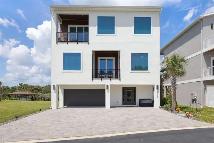 Contemporary three-story coastal home with clean lines, multiple balconies, and a spacious paver driveway—offering modern curb appeal just steps from the Ocean & Intercoastal.