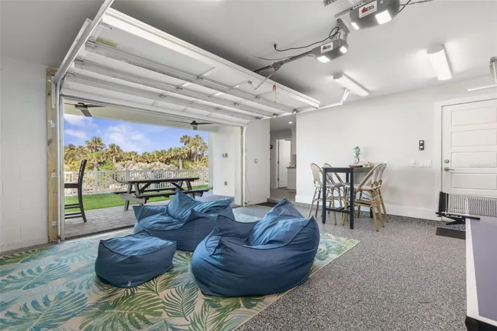 The first-floor game room opens directly to a fenced yard with a picnic table, bar-height seating, and a private hot tub—perfect for outdoor entertaining, relaxing, or enjoying the Florida sunshine