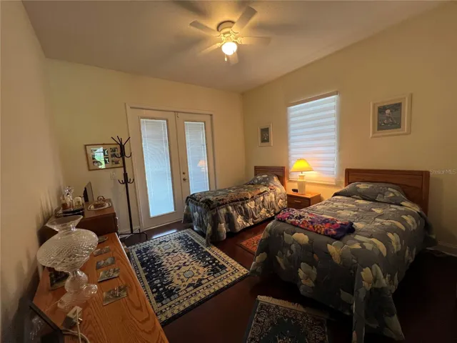 Guest bedroom 1 w/ french doors leading out to back lanai/pool area