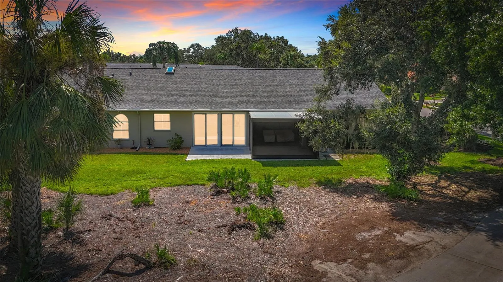 Evening view of villa rear with landscaped green space between villa and golf course