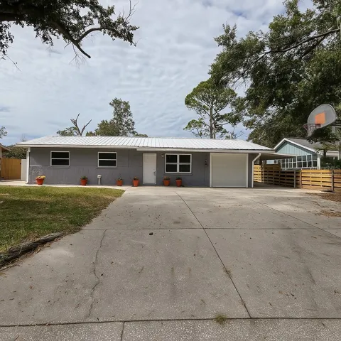 Front of the house with new metal roof. Picture has been virtually staged to add planters