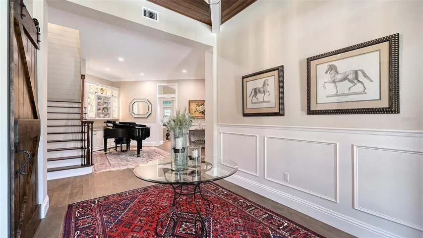 The foyer, measuring 13' x 10', warmly welcomes friends and family into your home. As you enter, you'll be greeted by the stunning staircase, featuring a red oak handrail complemented by aluminum decorative spindles in an aged bronze finish. The solid 1-1/2" wall with a poplar cap, engineered wood treads with painted risers, and a stylish carpet runner with a flared bottom tread create an inviting and elegant first impression.