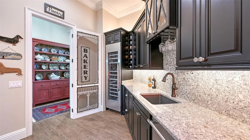 Step into the extensive butler's pantry, a true entertainer's dream! This remarkable space features a Scotsman clear ice maker and a Thermador wine refrigerator, ensuring you’re always ready to host in style. The elegant Elkay charcoal sink paired with a Delta bronze faucet adds a touch of sophistication, while the under-counter Thermador refrigerator keeps your essentials within easy reach. Beautiful granite countertops provide ample workspace, and the extensive Marsh Full Overlay cabinets offer both storage and style. This butler's pantry is not just functional; it’s a luxurious extension of your culinary experience!