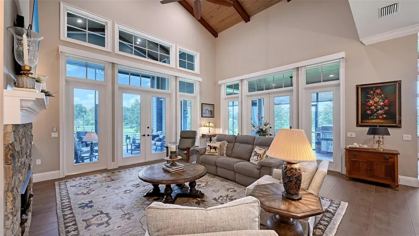 The Family Room features stunning tongue-and-groove ceilings that soar to an impressive 22', complemented by French doors that open to the remarkable outdoor entertainment area, seamlessly blending indoor and outdoor living.