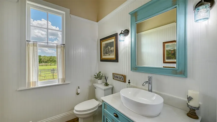 The powder bath, measuring 10' x 7', offers a serene retreat with picturesque views of the lush green back pastures. Adorned with exquisite Kotto Mattone 2" x 10" herringbone floor tile, the space exudes elegance and charm. The vertical T&G nickel gap walls add a touch of sophistication, creating a delightful atmosphere that makes this powder bath a perfect blend of style and tranquility.