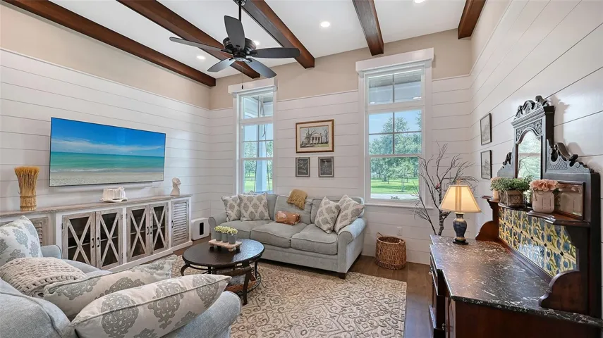 The Media Room, measuring 16' x 13', offers breathtaking views of the expansive front yard and serene lake. This inviting space is enhanced by painted poplar beams and elegant decorative wall treatments, creating a perfect atmosphere for relaxation and entertainment.