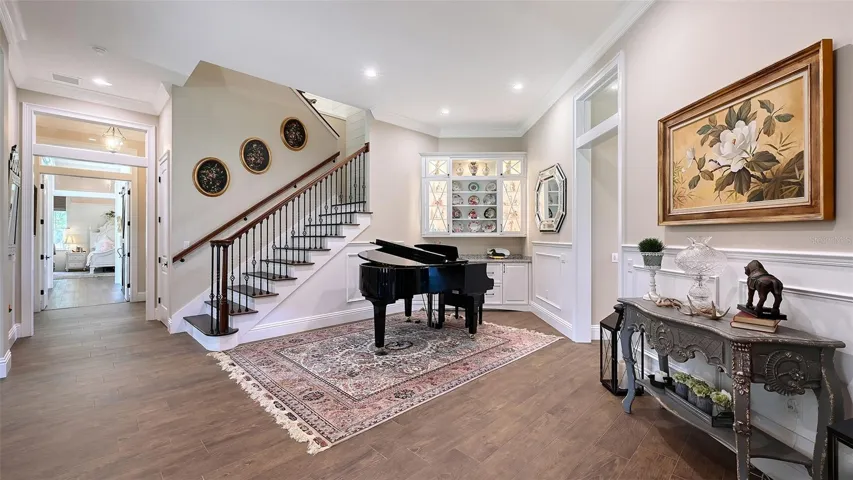 The Living Room, spanning 22' x 21' with soaring 12' ceilings, is an enchanting space that features delightful custom built-ins adorned with elegant lighting, making it the perfect setting to welcome friends and family. It showcases Marsh Full Overlay Level 8 & 10 maple cabinets, which include solid wood door frames, veneer center panels, dovetail drawers, and soft-close undermount guides, adding both functionality and charm to this inviting area.