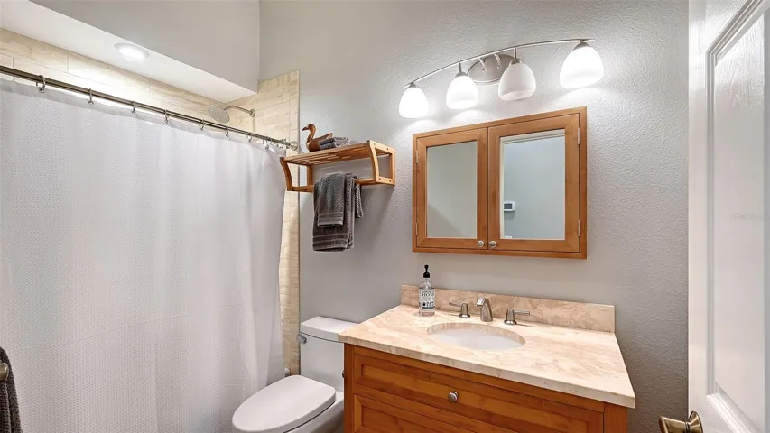 The guest bathroom has been perfectly renovated, striking a harmonious balance between modern elegance and warm charm. You'll appreciate the exquisite craftsmanship of the marble-topped sink and the rich bamboo wood accents that add a touch of sophistication. The beauty of the contemporary tile surrounding the tub enhances the overall aesthetic, creating a spa-like atmosphere. With an 80-gallon hot water heater, you can indulge in long, luxurious baths and showers without interruption, ensuring a truly relaxing experience every time you step into this stunning space!