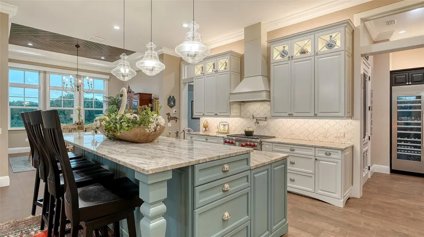 A Rohl apron-front white farm sink is paired with a Delta stainless steel faucet, a convenient pot filler, and an Insinkerator disposal, combining elegance with functionality.