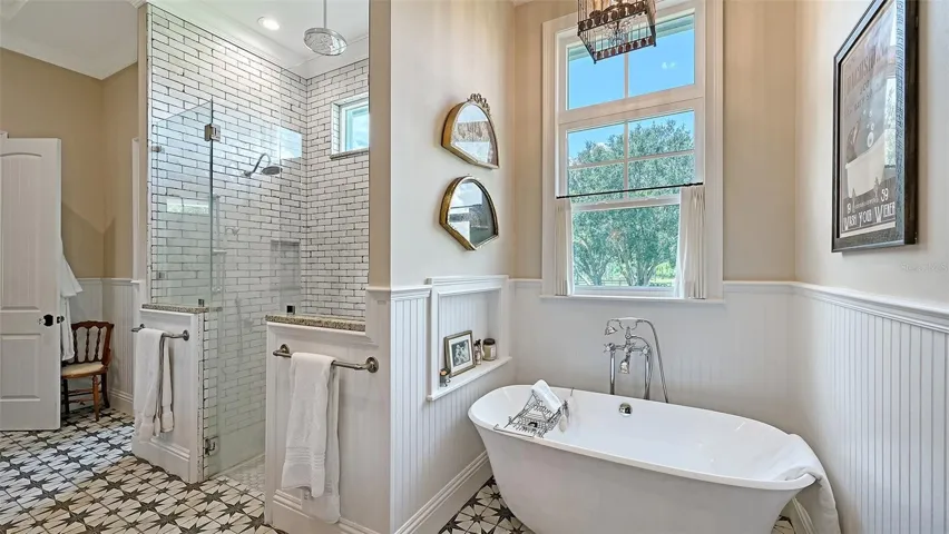 Step into the lavish shower, enclosed by 3/8" frameless glass with brushed nickel frames, showcasing beautiful Redeem Wax 8" x 40" wall tiles and a chic 2" x 2" mosaic shower floor.