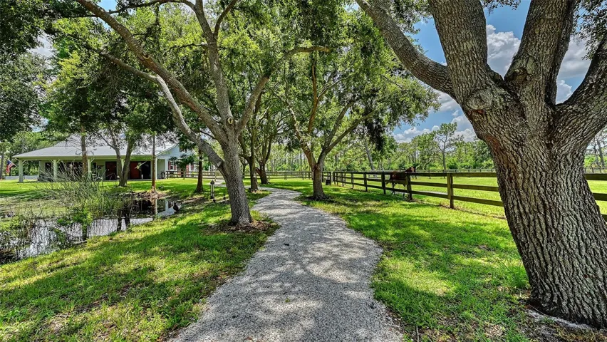 A beautiful pathway leads to the barn, and on the way, consider this IMPORTANT INFORMATION ABOUT THE MAIN HOUSE:  Flooring: The foyer, kitchen, living room, vestibule, storage closet, dining room, wet bar, pantry, A/C closet, hallway, laundry, and mud room are all adorned with Haven Barrel 8"x40" porcelain tile arranged in a random pattern. This elegant flooring is enhanced by two inlay transition borders off the kitchen, adding a touch of sophistication to the space.