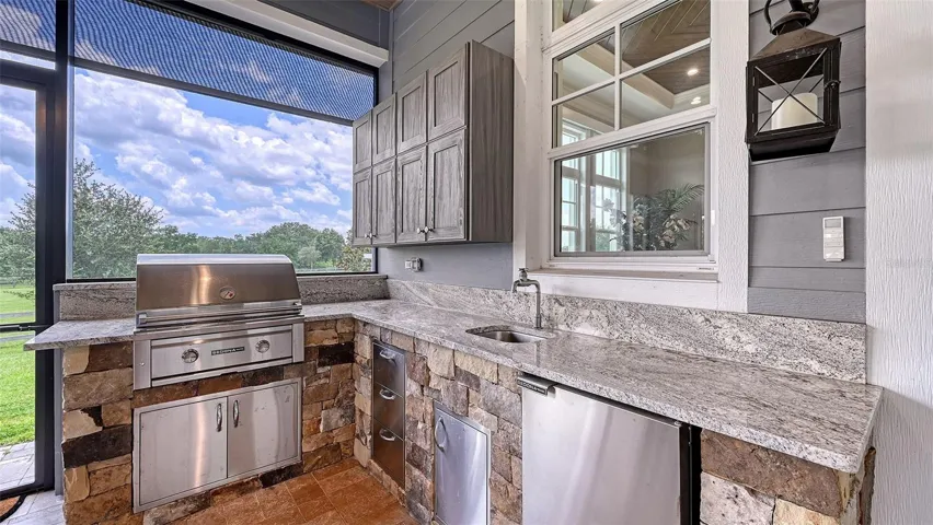 The outdoor kitchen is a culinary dream, featuring a Sedona 30" gas grill that promises to elevate your grilling game to new heights. With a 20" refrigerator at your fingertips, you’ll have everything you need to host unforgettable gatherings. The NatureKast cabinets provide ample storage while maintaining a stylish aesthetic, and the stunning ledge stone accents add a rustic charm that complements the natural surroundings.