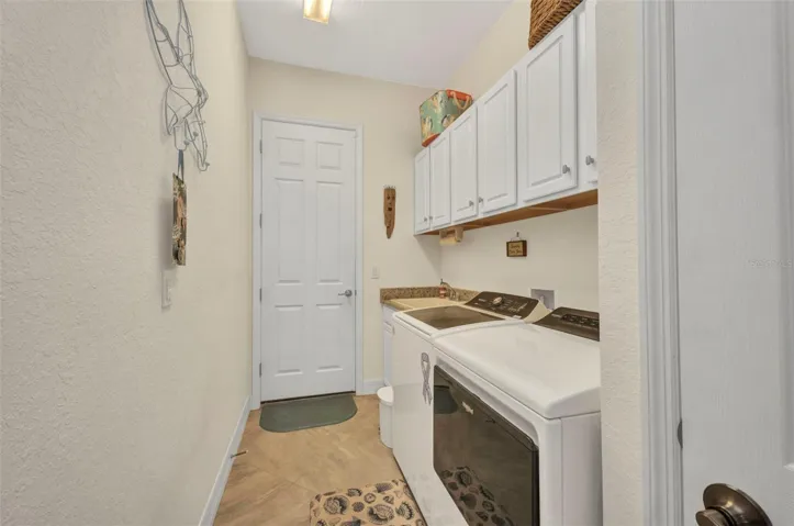 Functional Laundry room with full size washer/drink, utility sink and built-in cabinets. Door leads to garage.