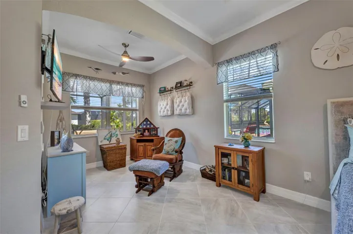 Sitting room with lighted fan and crown molding.