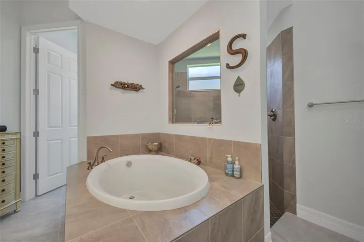 Spacious tiled shower stall with high window to the right.