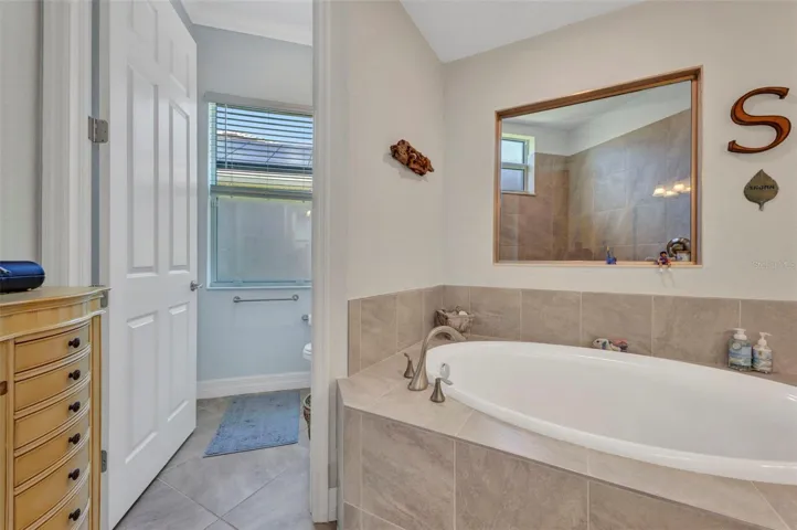Private water closet to left of garden tub. Shower stall through window behind tub.