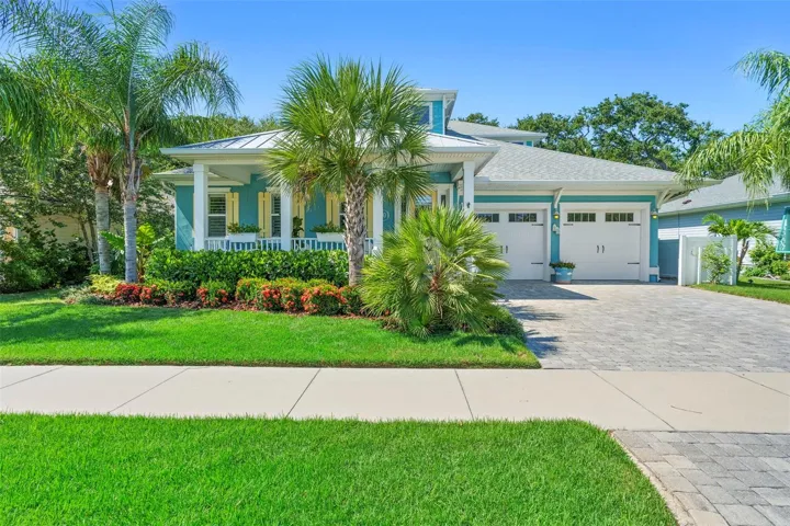 Beautiful curb appeal with manicured lawn, vibrant flowers, and swaying palms framing the home.”“Paver driveway leads to a spacious two-car garage and inviting front porch designed for coastal living,