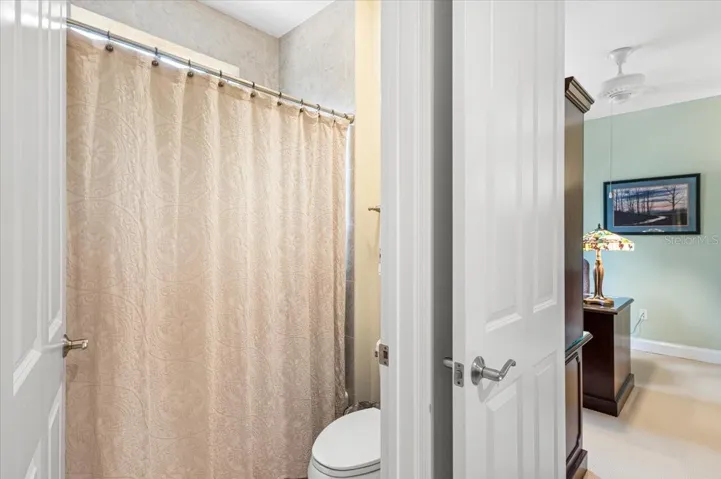 Tub/shower combo and toilet are separated from the double vanity by a door.