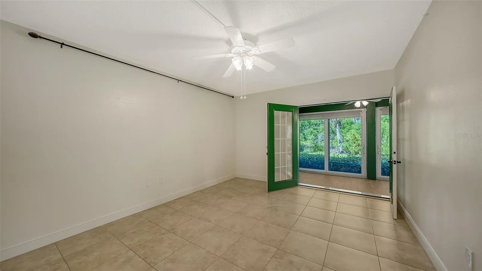 Primary bedroom with French doors leading to private enclosed lanai that runs the length of the unit.