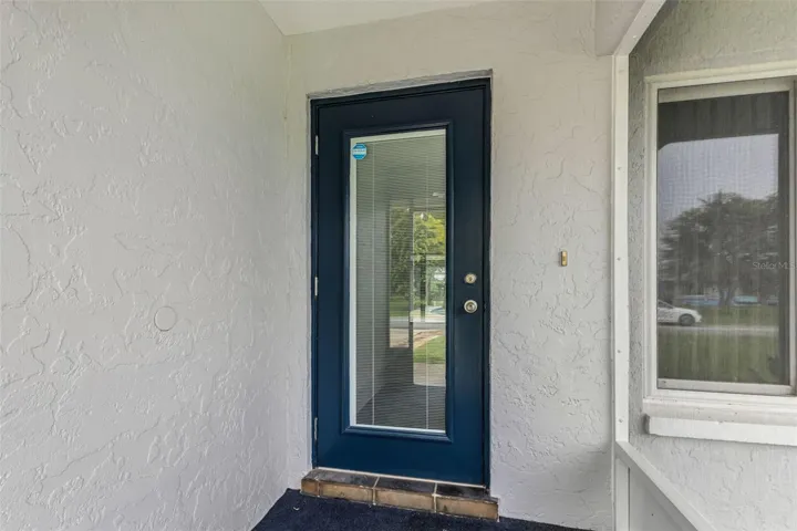 Impact door with blinds inside the glass and screened-in entryway.