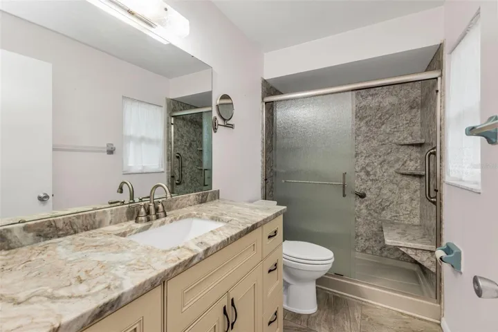 Primary Bathroom updated with  easy clean acrylic shower/shower seat, custom soft close cabinets and stone countertop