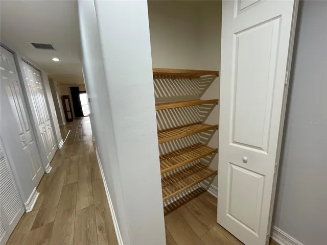 Hallway from the guest side of the home looking to the living area, showing many of the closets