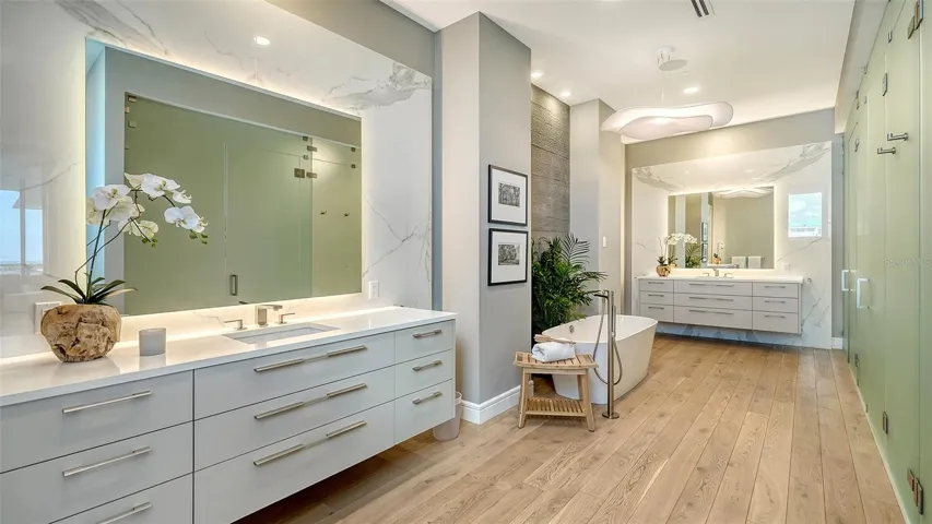 Spa-inspired primary bath with large-format Neolith™ porcelain, dual water closets, andToto™ one-piece comfort commodes