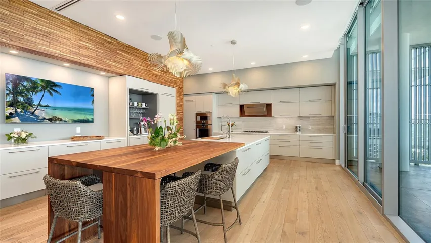 Gourmet kitchen with Gaggenau™ appliances, gas cooktop, Italian cabinetry, hiddencoffee bar, and a statement walnut island with matching accent wall