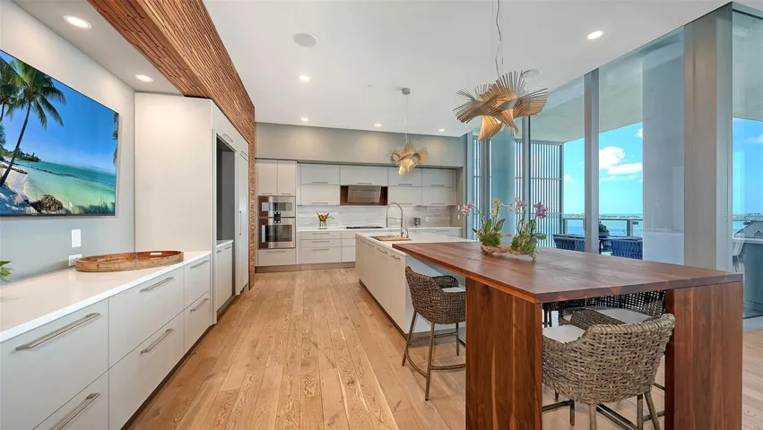 Gourmet kitchen with Gaggenau™ appliances, 5 burner gas cooktop, custom Italian cabinetry, hiddencoffee bar, and an oversized walnut island with complimenting accent wall.
