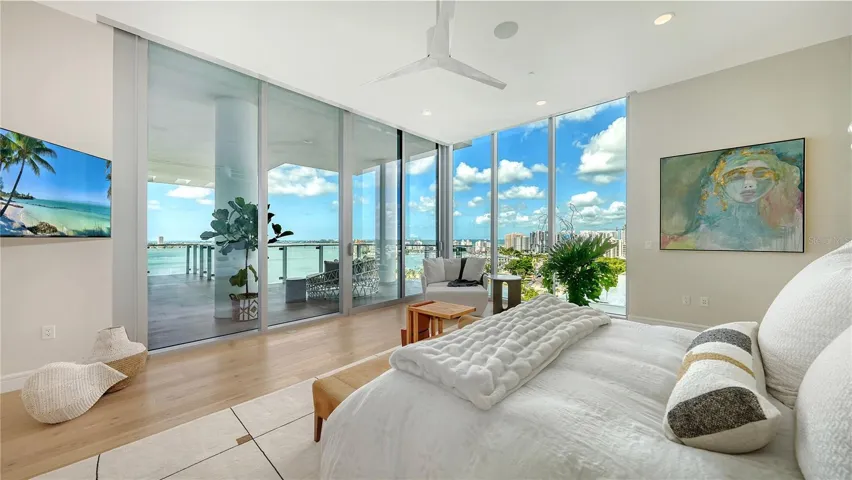 Wake up to your elevated paradise in this luxurious Primary bedroom, where floor-to-ceiling glass walls frame breathtaking water and city views. Thoughtfully designed for comfort and style, the space features Lutron™ room-darkening shades for ultimate privacy and relaxation