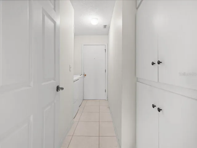 THE LAUNDRY ROOM HAS STORAGE CABINETS, TILE FLOOR AND EASY ACCESS TO THE GARAGE