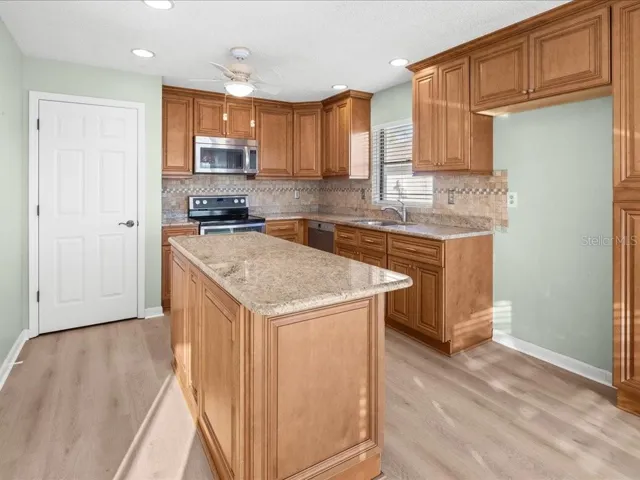 KITCHEN FEATURES NEWER CABINETRY WITH GRANITE COUNTER TOP AND PANTRY.