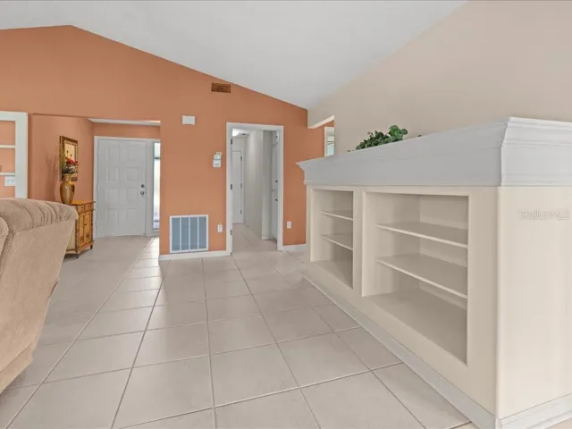 VIEW OF THE GREAT TOWARDS THE FOYER ON LEFT. THE MIDDLE DOORWAY IS THE LAUNDRY ROOM AND GARAGE. THE GUEST BEDROOM IS ON THE RIGHT PAST THE BOOKCASE.