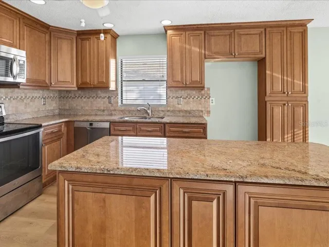KITCHEN HAS TILED BACKSPLASH AND LARGE ISLAND.