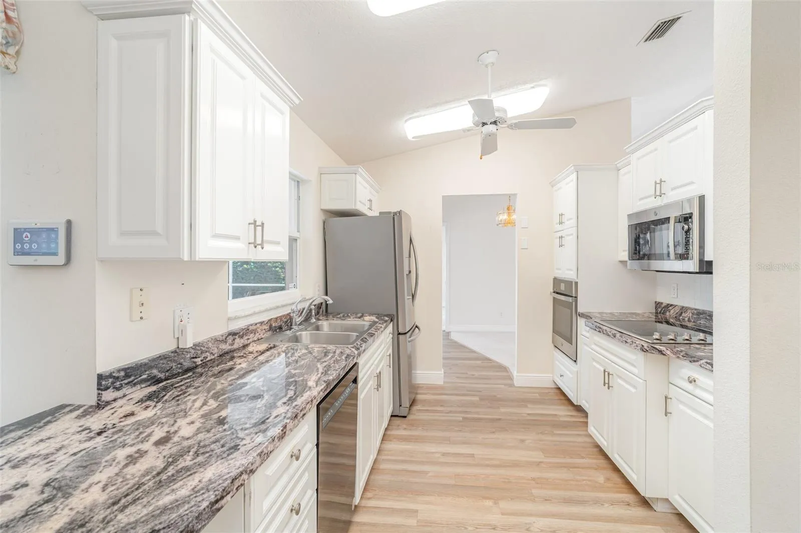 Modern kitchen with white cabinetry, granite countertops, and stainless steel appliances in an open-concept floor plan.