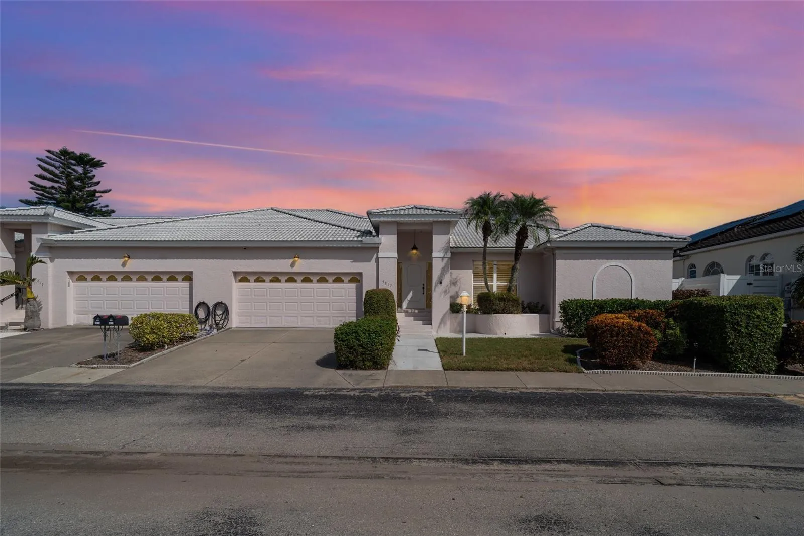 Front exterior view of a modern single-family home in Bradenton, featuring a manicured lawn and sunset lighting. Ideally located near Anna Maria Island and Bradenton beaches.