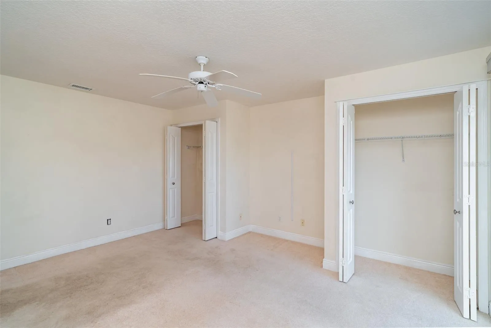 Clean, neutral-toned secondary bedroom showing versatile space for furniture placement.