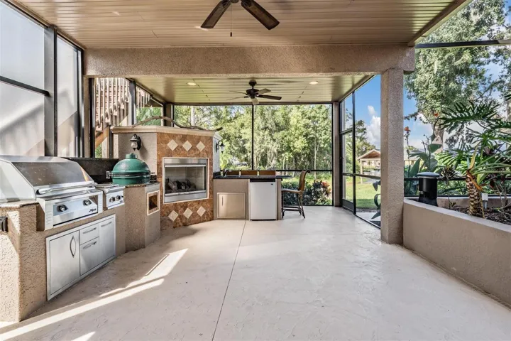 Ourdoor kitchen with Green Egg smoker, BBQ grill, sink, fireplace, and mini fridge