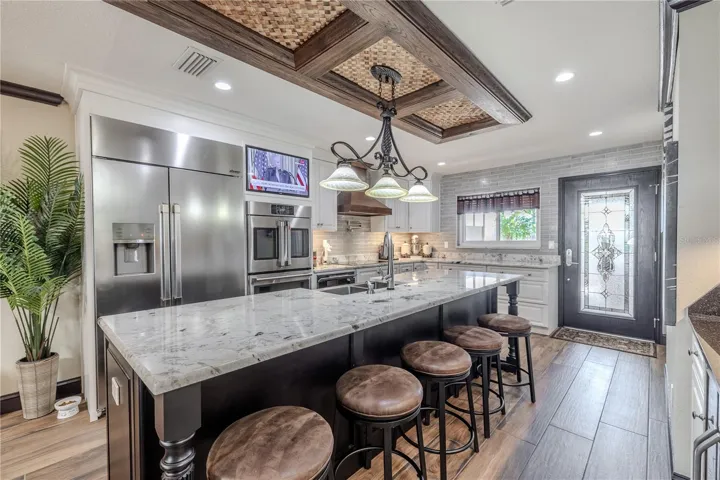 Custom cabinetry, under-cabinet lighting, and a pot filler combine functionality and style, while the built-in TV nook keeps the space perfect for entertaining.