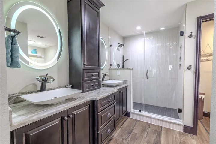 Relax in a spa-like setting featuring a jetted soaking tub, walk-in rainfall shower, and built-in linen storage that keeps everything beautifully organized.