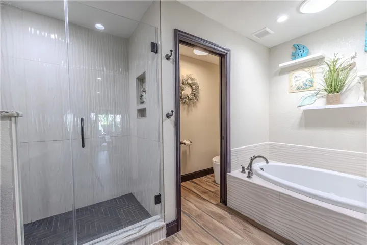 The primary walk-in shower features a rainfall showerhead, seamless glass enclosure, and elegant tile that extends floor to ceiling for a spa-like finish.