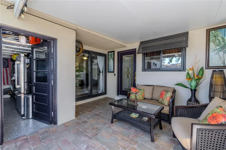 The front patio courtyard offers a peaceful outdoor retreat with brick pavers, a mounted fan, and direct access to both the garage and the second bedroom.