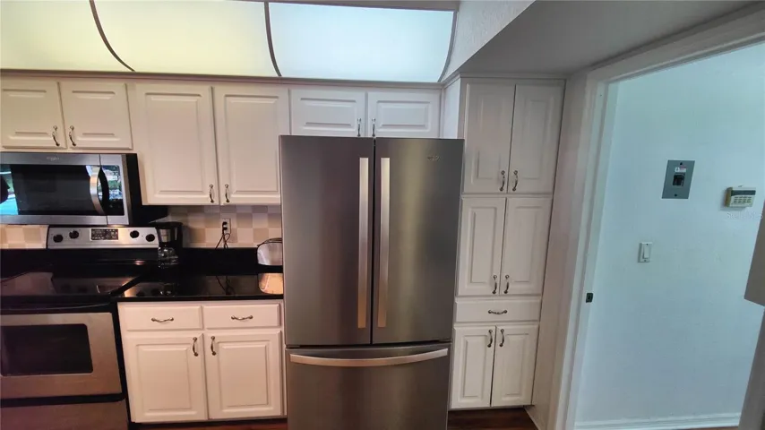 Kitchen double door refrigerator has a large slide out drawer freezer underneath.  New range features an easy clean smooth cooking surface. Kitchen has lots of custom storage cabinets and drawers for easy organization