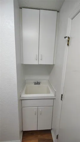 Laundry room sink has more storage cabinets above and underneath it.